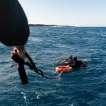 Deadly Dive: Maldivian Cave Mystery Two scuba divers in the ocean being assisted by a person holding a rescue line