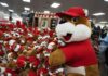 A large plush mascot surrounded by smaller stuffed animals in a store