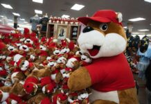 A large plush mascot surrounded by smaller stuffed animals in a store