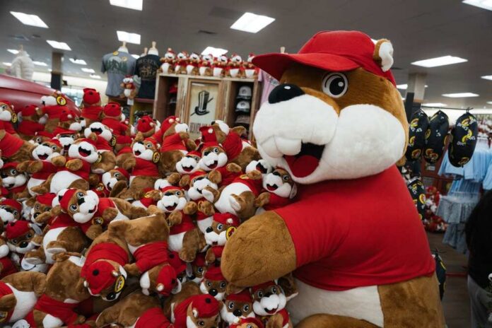 A large plush mascot surrounded by smaller stuffed animals in a store
