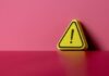 Yellow triangular warning sign on a pink background