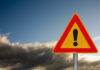 Lethal Umbrella: Freak Gust Turns Deadly A triangular warning sign with an exclamation mark against a cloudy sky