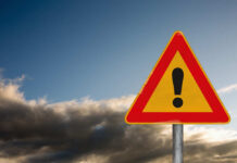 Lethal Umbrella: Freak Gust Turns Deadly A triangular warning sign with an exclamation mark against a cloudy sky