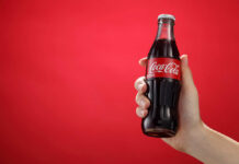 Coca-Cola Shutters Century-Old Facility Red sign with a white cross symbol on a dark background