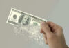 Bank Heist 2.0: Your Money Vanishes in Minutes Hand holding a disintegrating hundred dollar bill.