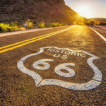 Historic Route 66 sign painted on a road at sunset