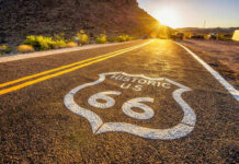 Historic Route 66 sign painted on a road at sunset
