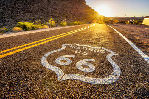 Historic Route 66 sign painted on a road at sunset