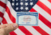 Social Security Doomed? Is THIS the Answer? Hand holding social security card, American flag background.