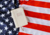 Bible Mandate Sparks Church-State Brawl Bible on an American flag background.
