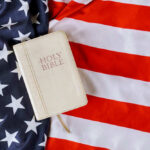 Bible Mandate Sparks Church-State Brawl Bible on an American flag background.