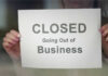 Small-Town Gut Punch: THESE Stores Vanish A person holding a sign that reads 'CLOSED Going Out of Business'