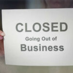 Small-Town Gut Punch: THESE Stores Vanish A person holding a sign that reads 'CLOSED Going Out of Business'