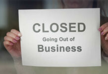 Small-Town Gut Punch: THESE Stores Vanish A person holding a sign that reads 'CLOSED Going Out of Business'