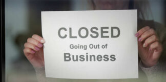 A person holding a sign that reads 'CLOSED Going Out of Business'