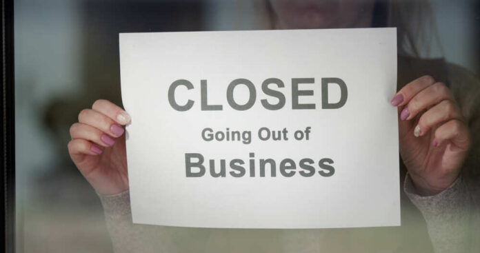 Worker,Hangs,A,Banner,Closed,Going,Out,Of,Business,On A person holding a sign that reads 'CLOSED Going Out of Business'