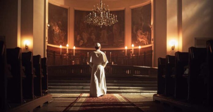 A religious figure standing in a church with candlelight illuminating the space