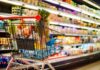 Shopping cart filled with various groceries in a supermarket aisle