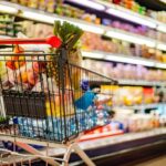 Shopping cart filled with various groceries in a supermarket aisle
