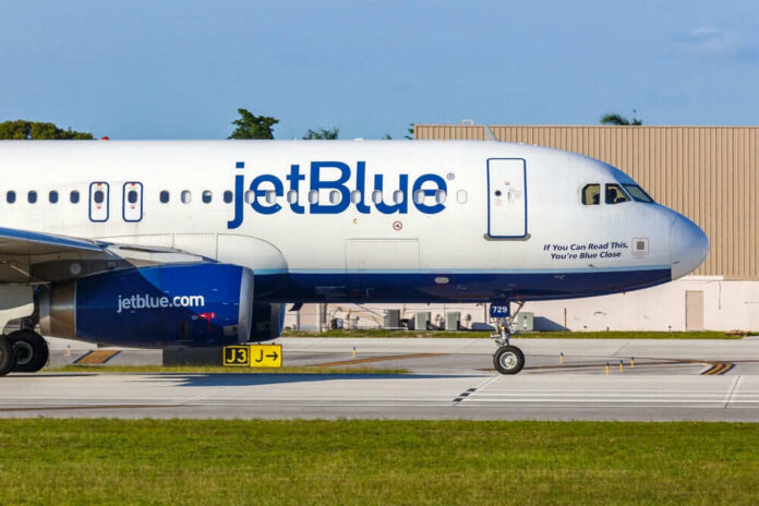 shutterstock_2274366343 JetBlue airplane taxiing on airport runway.