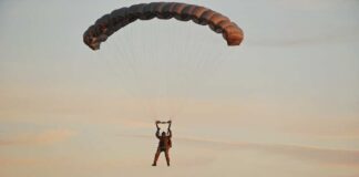 Silhouette of a helicopter with two individuals being lowered by ropes