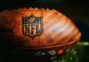 NFL Phenom Dead at 36 — What Happened? Close-up of an NFL football on grass.