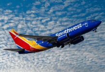 Southwest airplane on the air with blu sky and white clouds.