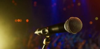 Close-up of a microphone in front of a blurred audience at a concert