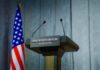 Press podium with the White House sign and an American flag in the background