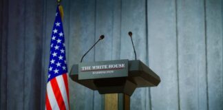 Press podium with the White House sign and an American flag in the background
