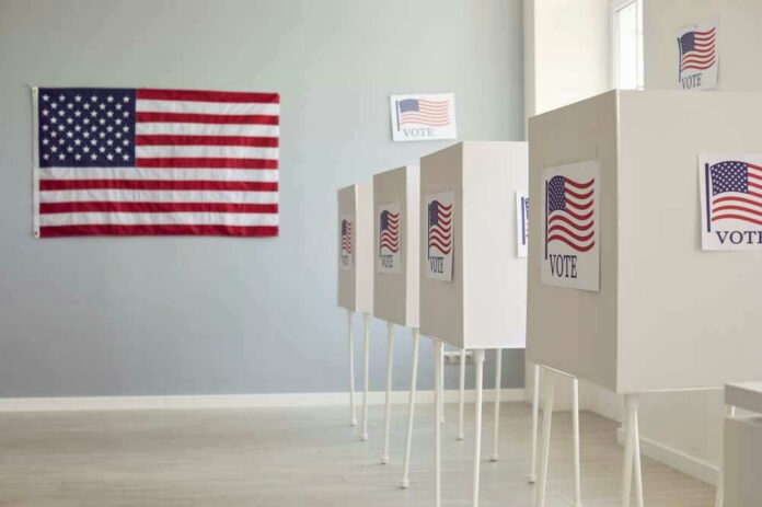 shutterstock_2475726979-1 Polling booths with American flags and Vote signs.