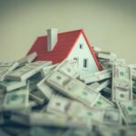 Congress’ Housing Fix Backfires? A small model house surrounded by stacks of money