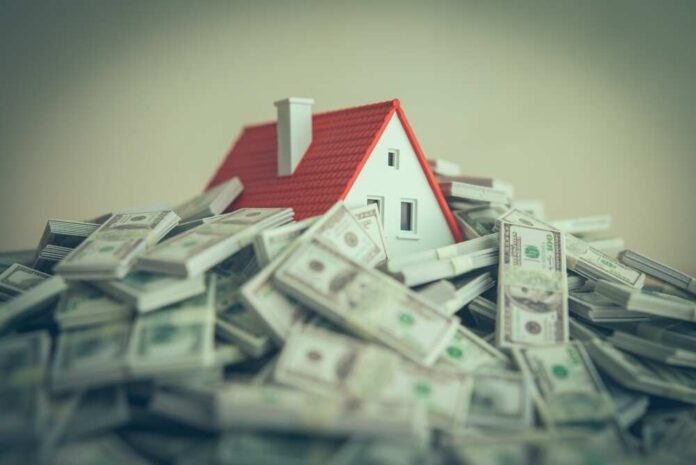 A,House,Drowning,In,Heap,Us,Dollar,Banknotes.,Debt,From A small model house surrounded by stacks of money