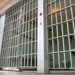 Detention Boom Soars — 43,138 Arrests! Empty prison cell with metal bars and toilet.