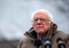 Bernie Sanders Targets THESE Billions?! Bernie Sanders wearing glasses speaking outdoors with microphones.