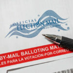 Voter Rolls CORRUPTED – Illegal Votes Cast Vote-by-mail envelope with pen on top.