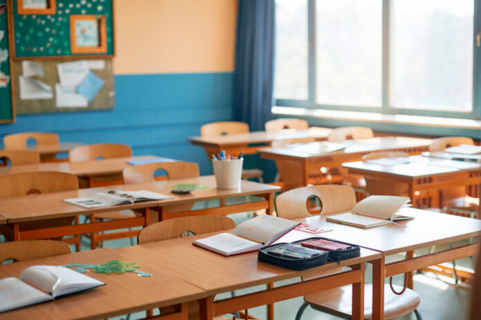 Classroom,Without,Children,In,Primary,School. Police car lights with officers blurred in background.
