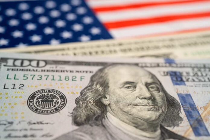 Usa,Dollar,Banknotes,On,America,Flag,,Business,And,Finance,Concept. Close-up of a hundred dollar bill in front of an American flag