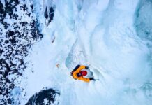 1,500-Foot Plunge — She Lived A climber ascending a frozen ice wall in a snowy landscape