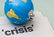 NOW: Gulf Chokepoint Explodes As Missiles Fly A small globe resting on a newspaper with the word 'crisis'
