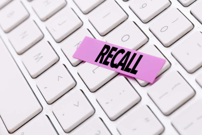 Recall A pink sticky note with the word 'RECALL' placed on a white keyboard