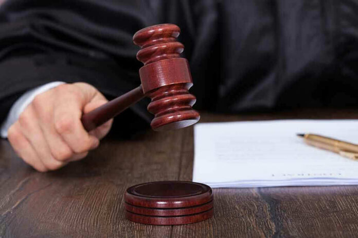 186812807 Judges hand holding gavel next to documents.
