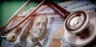 A stethoscope resting on a stack of hundred-dollar bills