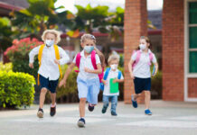 Measles Danger Rises: Kindergarten Exemptions Spike Children with backpacks and masks running outside school.