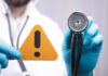Doctor with stethoscope holding a warning sign