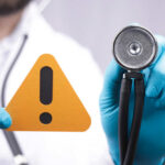 Doctor with stethoscope holding a warning sign