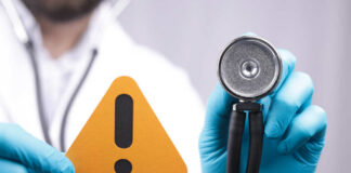 Doctor with stethoscope holding a warning sign