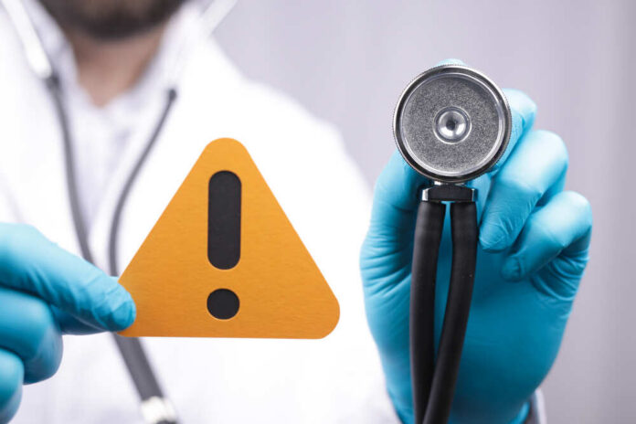 Doctor with stethoscope holding a warning sign
