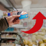 Hand holding credit cards with red upward arrow