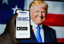 Smartphone displaying Truth Social app, Donald Trump background.